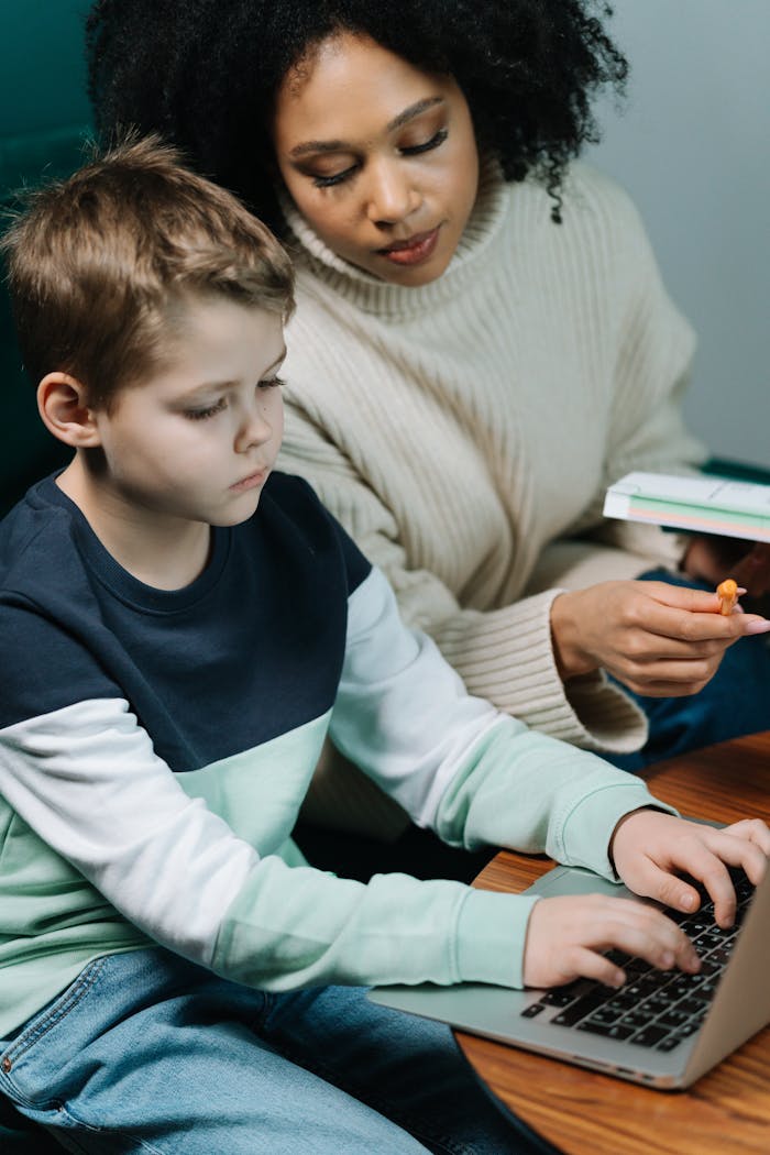 services-04 A dedicated tutor helps a young boy with his homework on a laptop, fostering learning.