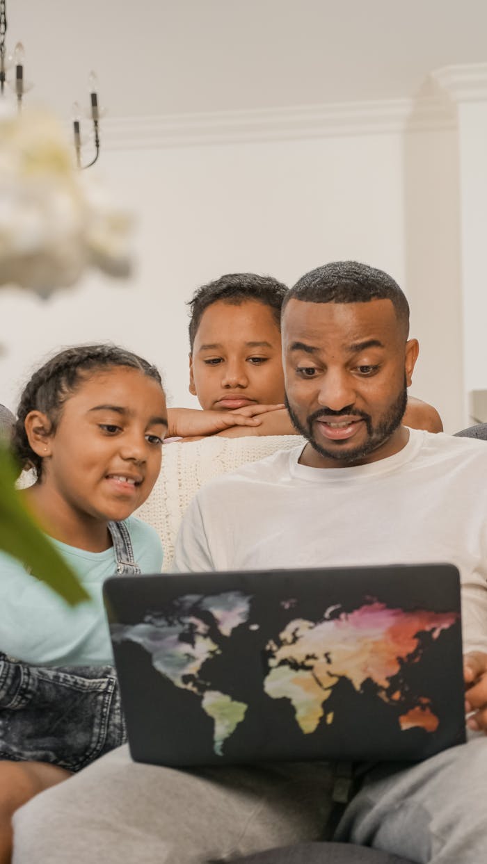 services-02 Father bonding with kids using a laptop in a cozy living room setting.